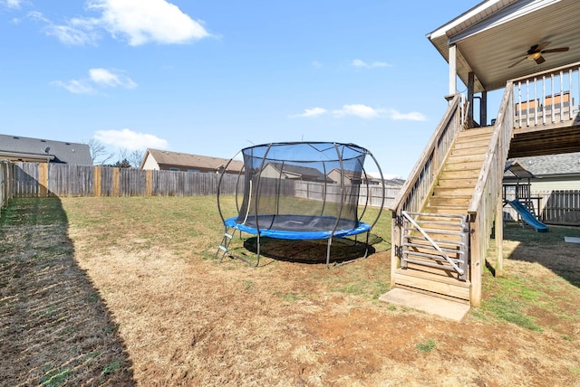 view of yard with a trampoline, a playground, stairway, ceiling fan, and a fenced backyard