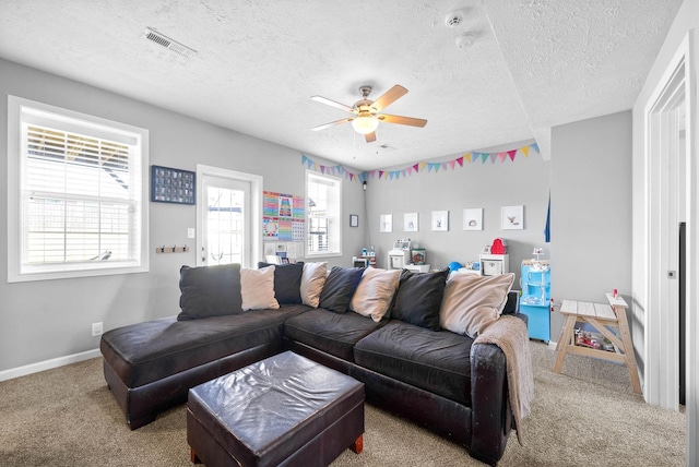 carpeted living area with a textured ceiling, a ceiling fan, visible vents, and baseboards