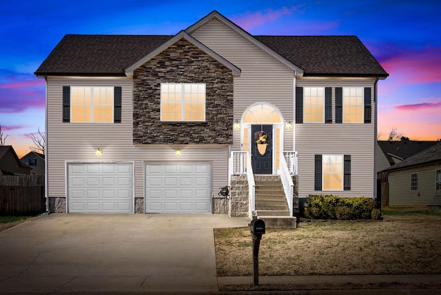 view of front of property featuring driveway, a garage, stone siding, roof with shingles, and fence