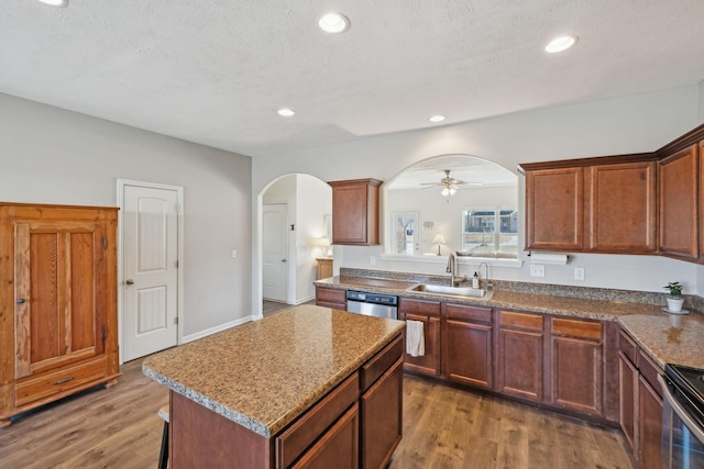 kitchen with light wood-type flooring, arched walkways, stainless steel appliances, and a sink