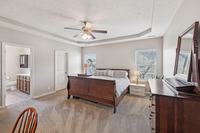 bedroom with light carpet, baseboards, visible vents, a tray ceiling, and a textured ceiling