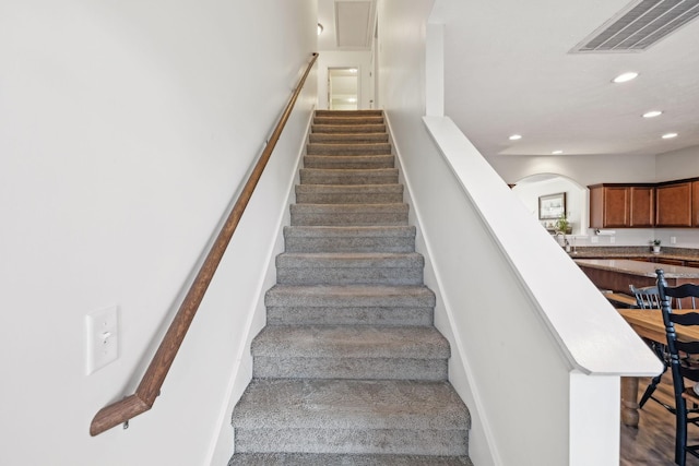 staircase featuring arched walkways, carpet, recessed lighting, visible vents, and baseboards