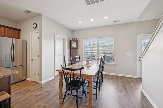 dining space with dark wood-style flooring, visible vents, and baseboards