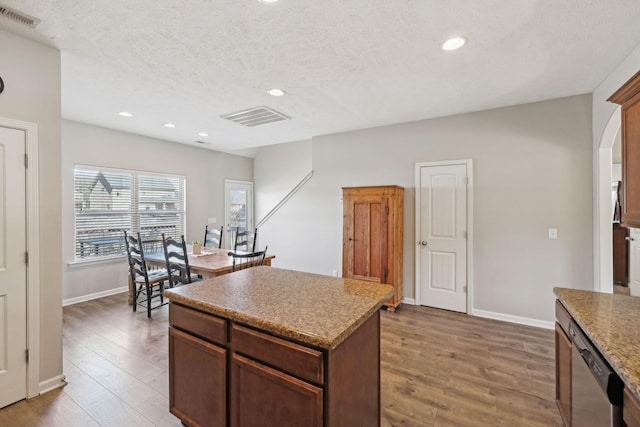 kitchen with arched walkways, visible vents, light wood finished floors, and stainless steel dishwasher