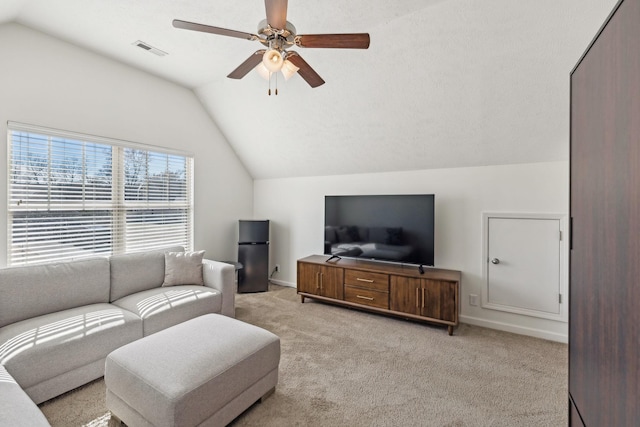 living room featuring vaulted ceiling, a ceiling fan, visible vents, and light colored carpet