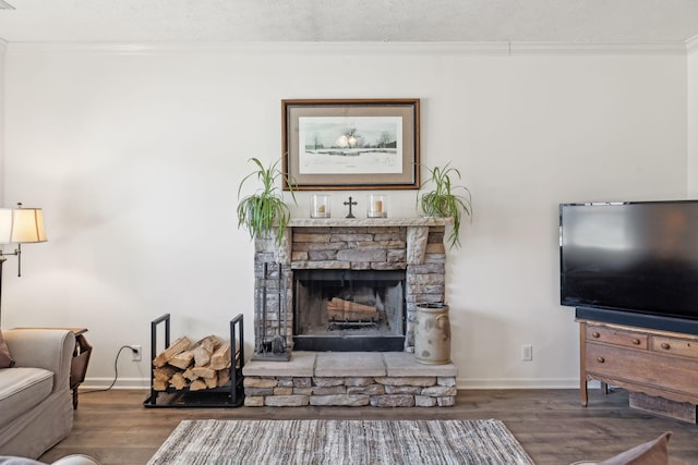 living room featuring ornamental molding, a stone fireplace, baseboards, and wood finished floors