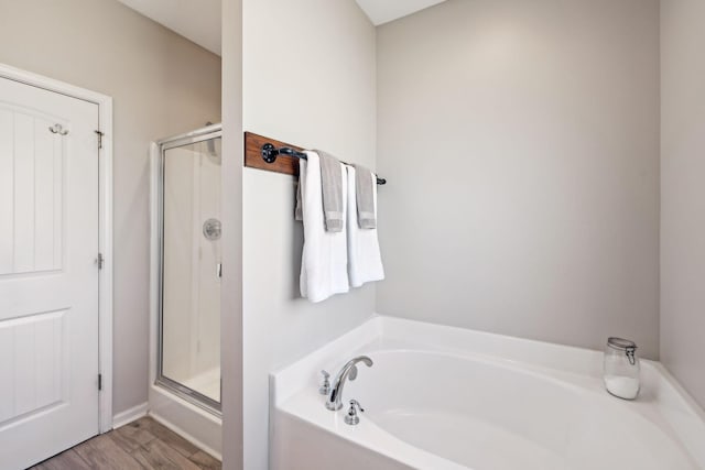 bathroom with a stall shower, a garden tub, and wood finished floors