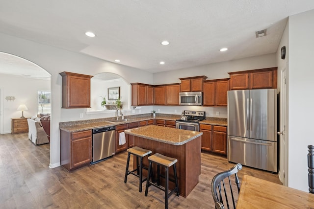 kitchen with appliances with stainless steel finishes, arched walkways, and wood finished floors