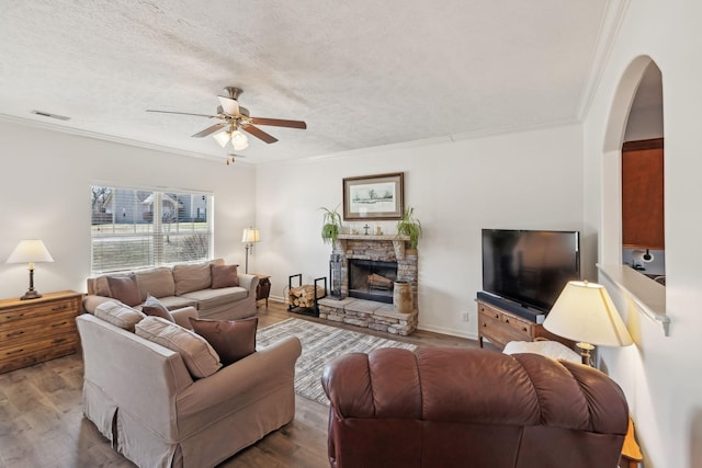 living area with visible vents, crown molding, a textured ceiling, and wood finished floors