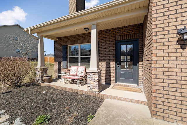 entrance to property with a porch and brick siding