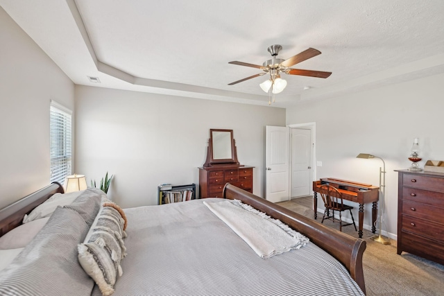 carpeted bedroom with ceiling fan, visible vents, baseboards, and a raised ceiling