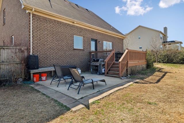 rear view of house featuring a patio area, brick siding, a lawn, and a wooden deck