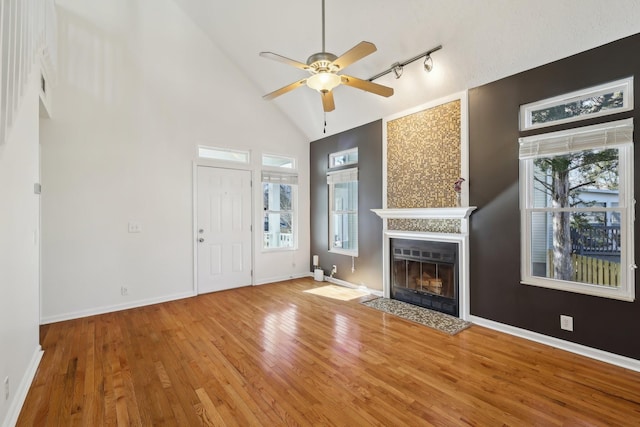 unfurnished living room with baseboards, hardwood / wood-style floors, a fireplace with flush hearth, and a healthy amount of sunlight