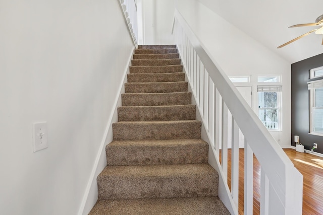 stairs with lofted ceiling, ceiling fan, baseboards, and wood finished floors