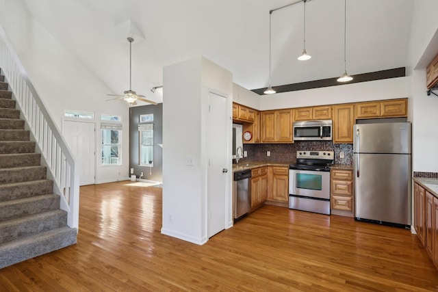 kitchen with high vaulted ceiling, appliances with stainless steel finishes, open floor plan, and a sink