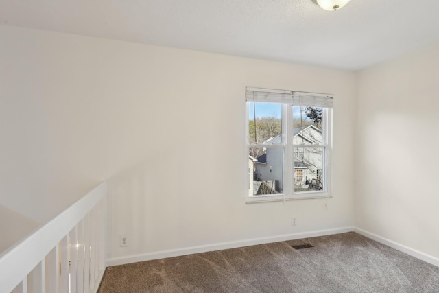 empty room featuring carpet floors, visible vents, and baseboards