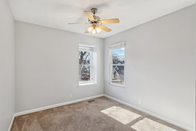 spare room with ceiling fan, carpet flooring, visible vents, and baseboards