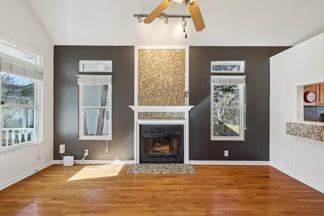 unfurnished living room featuring plenty of natural light, a fireplace, baseboards, and wood finished floors