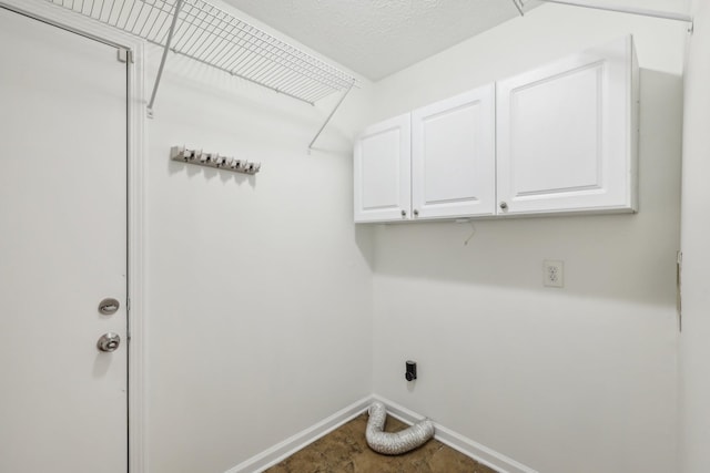 clothes washing area featuring cabinet space, hookup for an electric dryer, a textured ceiling, and baseboards