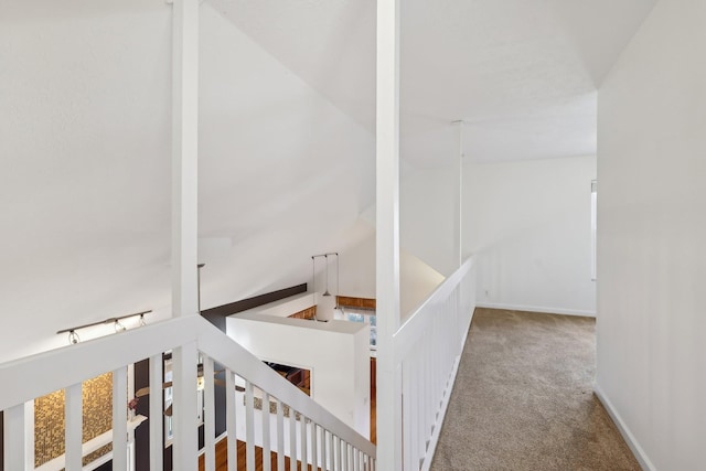 hallway with carpet, baseboards, and an upstairs landing