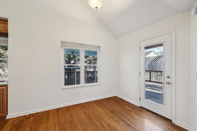 unfurnished room with vaulted ceiling, wood-type flooring, and baseboards