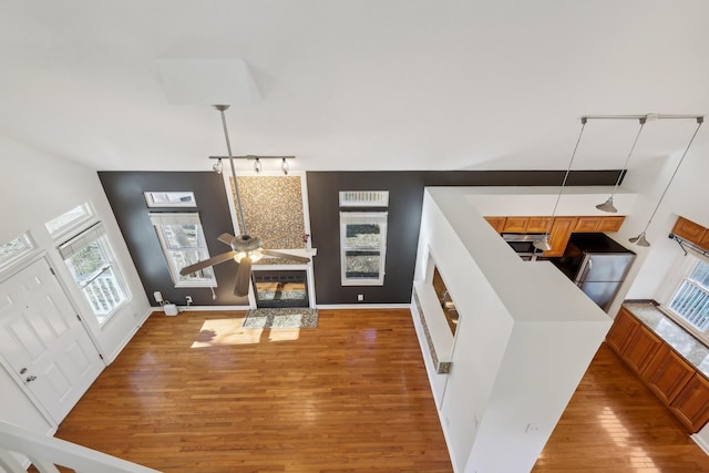 foyer with light wood-type flooring, baseboards, a ceiling fan, and a glass covered fireplace