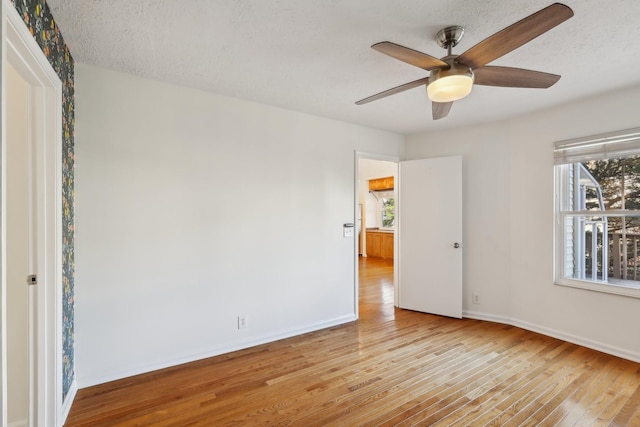 spare room featuring a textured ceiling, ceiling fan, hardwood / wood-style flooring, and baseboards