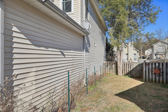 view of home's exterior featuring a lawn, fence, and a residential view