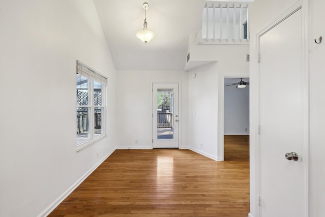 entrance foyer with high vaulted ceiling, baseboards, and wood finished floors