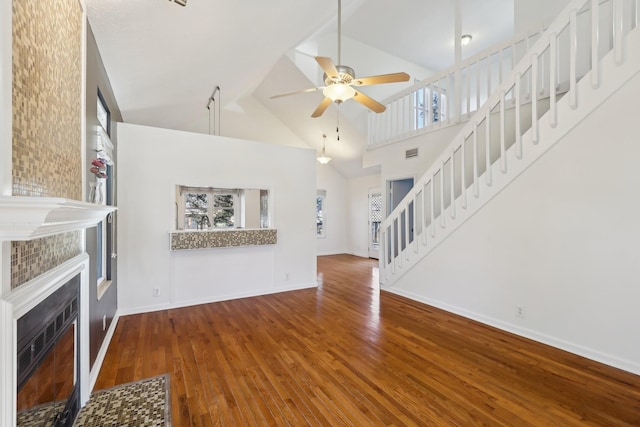 unfurnished living room with baseboards, a fireplace, stairway, and wood finished floors