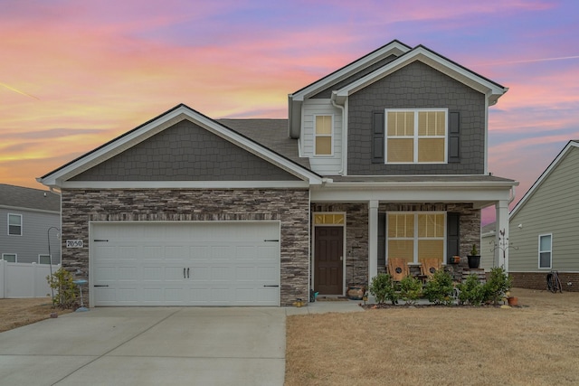 craftsman inspired home with covered porch, concrete driveway, stone siding, and a garage