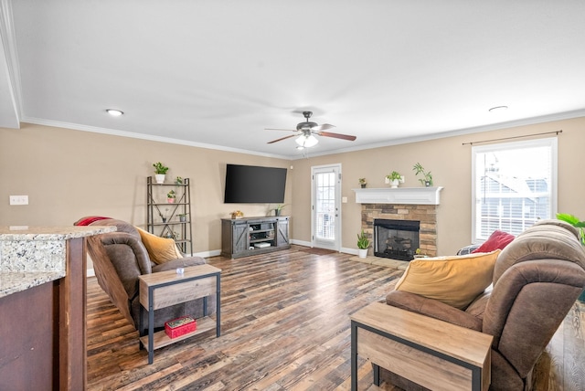 living area featuring a fireplace, ornamental molding, a ceiling fan, wood finished floors, and baseboards