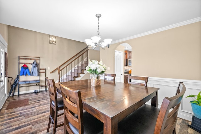 dining room with an inviting chandelier, arched walkways, dark wood finished floors, and ornamental molding