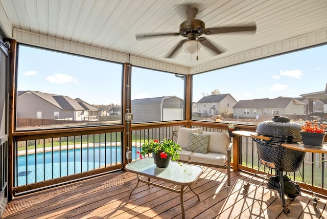 sunroom / solarium featuring ceiling fan and a residential view