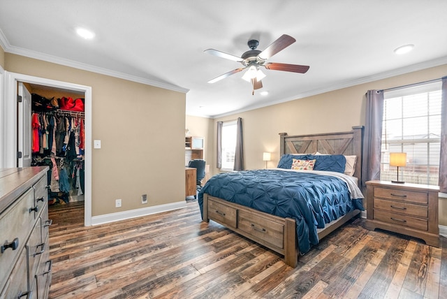 bedroom featuring dark wood-style floors, baseboards, ornamental molding, and a walk in closet