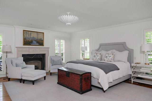 bedroom with light wood finished floors, a fireplace, and crown molding