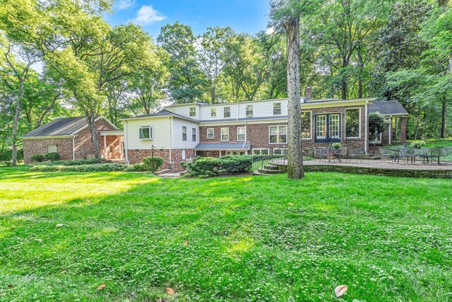 back of property with a patio area, brick siding, and a yard