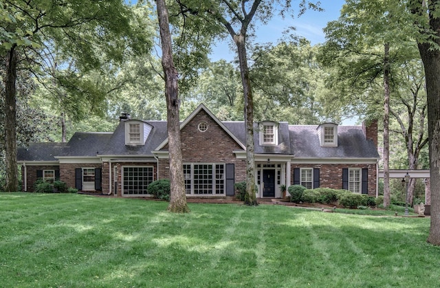 back of house featuring brick siding, a yard, and a chimney