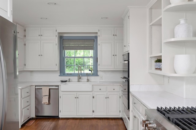 kitchen with appliances with stainless steel finishes, open shelves, a sink, and light countertops