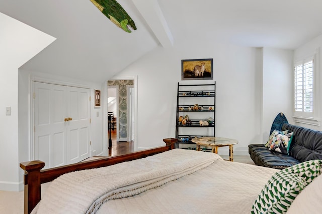 bedroom featuring lofted ceiling with beams, a closet, and baseboards