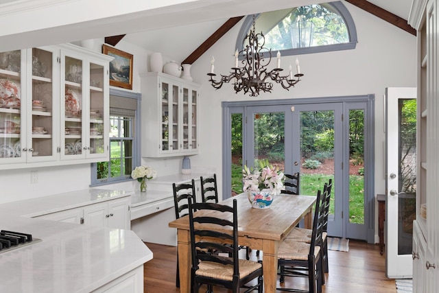 dining area featuring a chandelier, french doors, lofted ceiling with beams, and wood finished floors