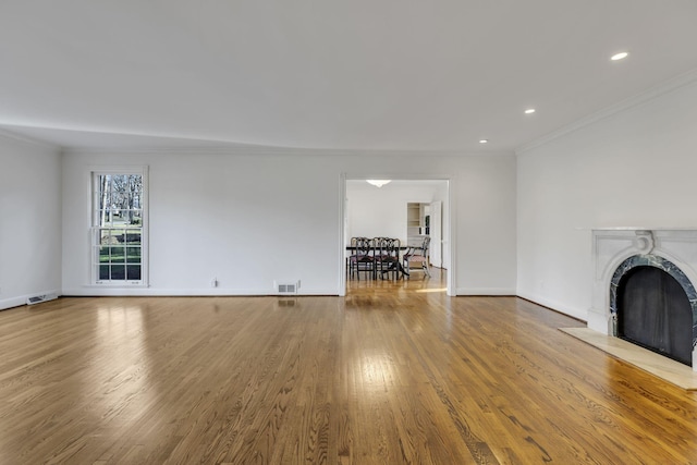 unfurnished living room with ornamental molding, wood finished floors, visible vents, and baseboards