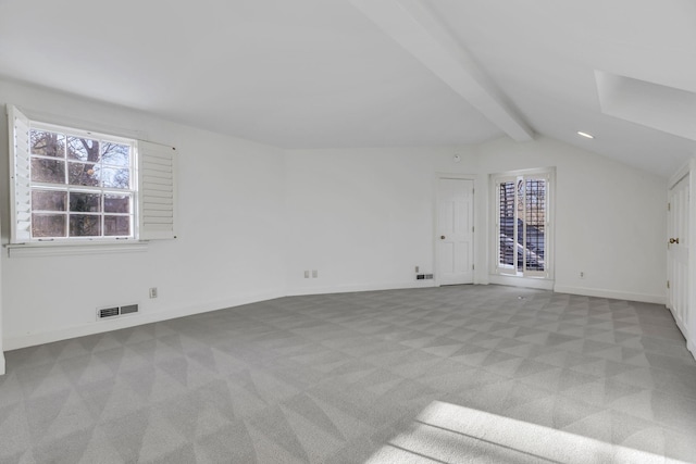 interior space with light carpet, vaulted ceiling with beams, baseboards, and visible vents