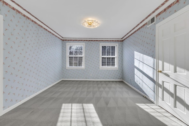 spare room with visible vents, ornamental molding, carpet flooring, baseboards, and wallpapered walls