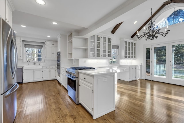 kitchen featuring stainless steel appliances, white cabinets, lofted ceiling with beams, and wood finished floors