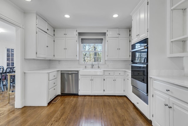 kitchen with double wall oven, light countertops, a sink, and stainless steel dishwasher