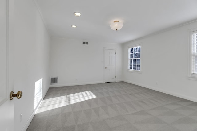 empty room featuring light carpet, visible vents, and baseboards