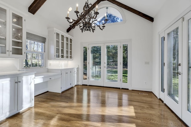 interior space with an inviting chandelier, wood finished floors, beam ceiling, and french doors