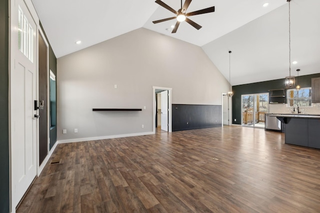 unfurnished living room with high vaulted ceiling, visible vents, dark wood finished floors, and ceiling fan with notable chandelier