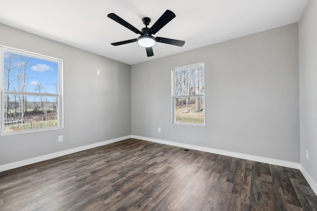 spare room with ceiling fan, baseboards, dark wood finished floors, and a wealth of natural light